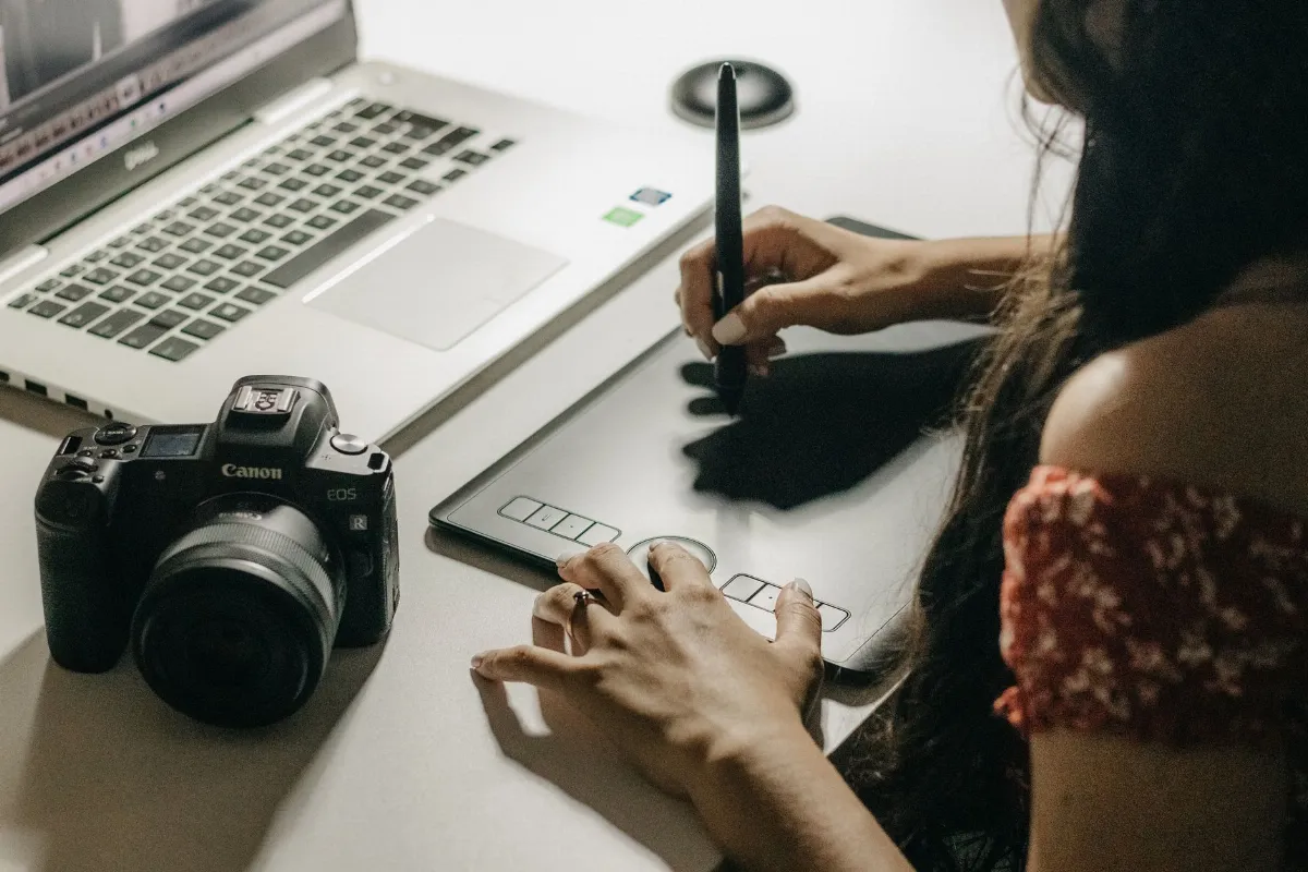 Diseñadora usando tableta gráfica y laptop para crear un catálogo en Canva