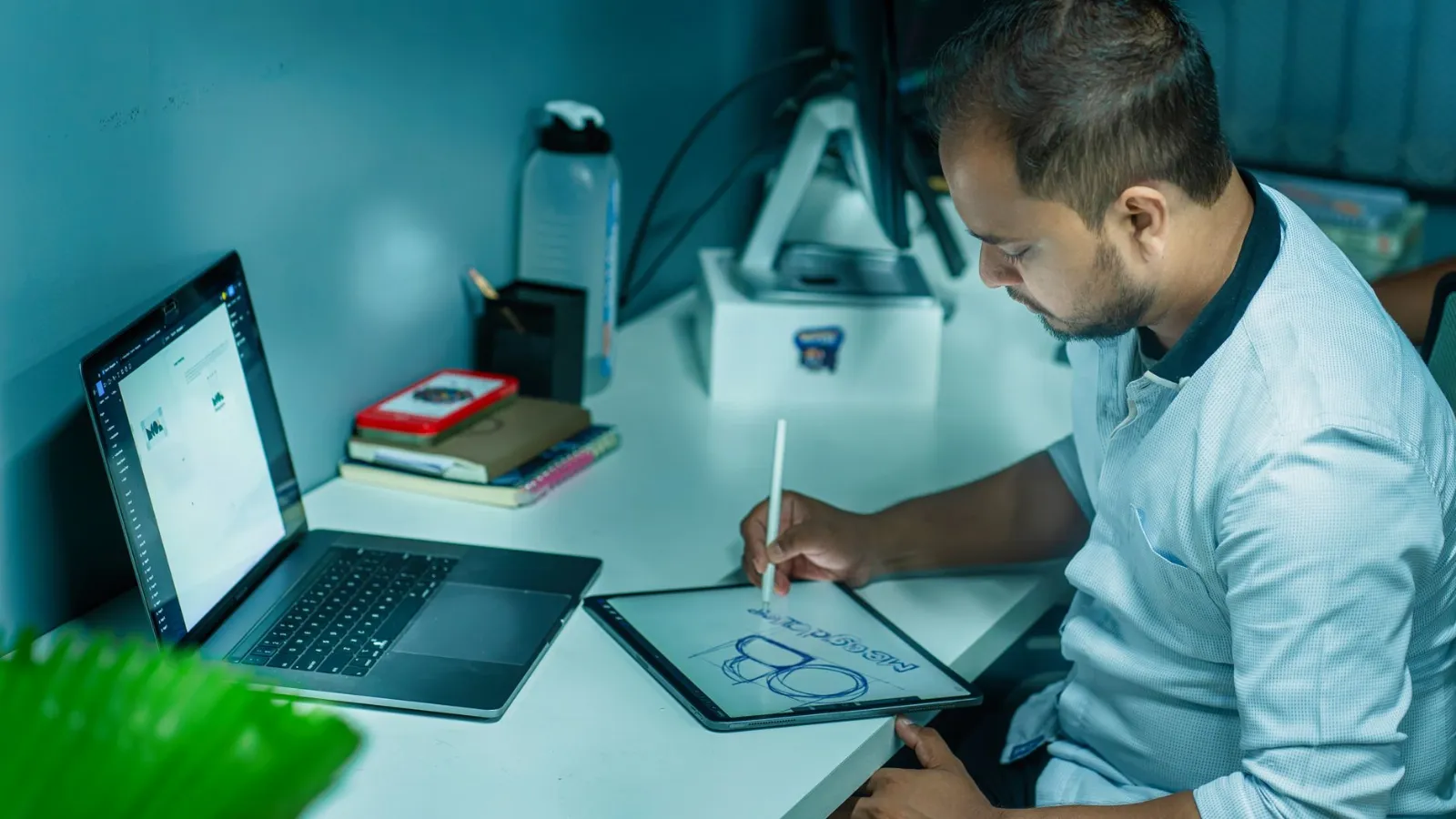 Diseñador trabajando en una tableta junto a su laptop para armar un catálogo en Canva