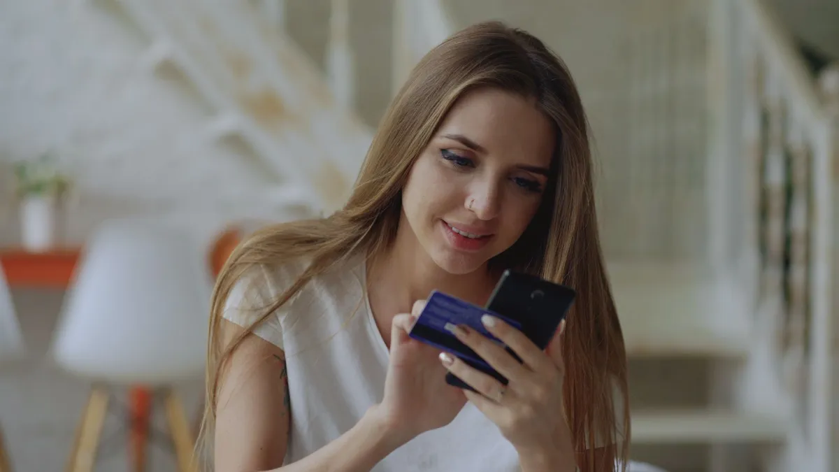Mujer comprando en línea desde su celular, ejemplo de catálogo en línea para ver productos desde el teléfono